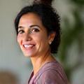 Portrait of Maria Gonzalez, a warm and empathetic licensed massage therapist, offering a comforting smile.